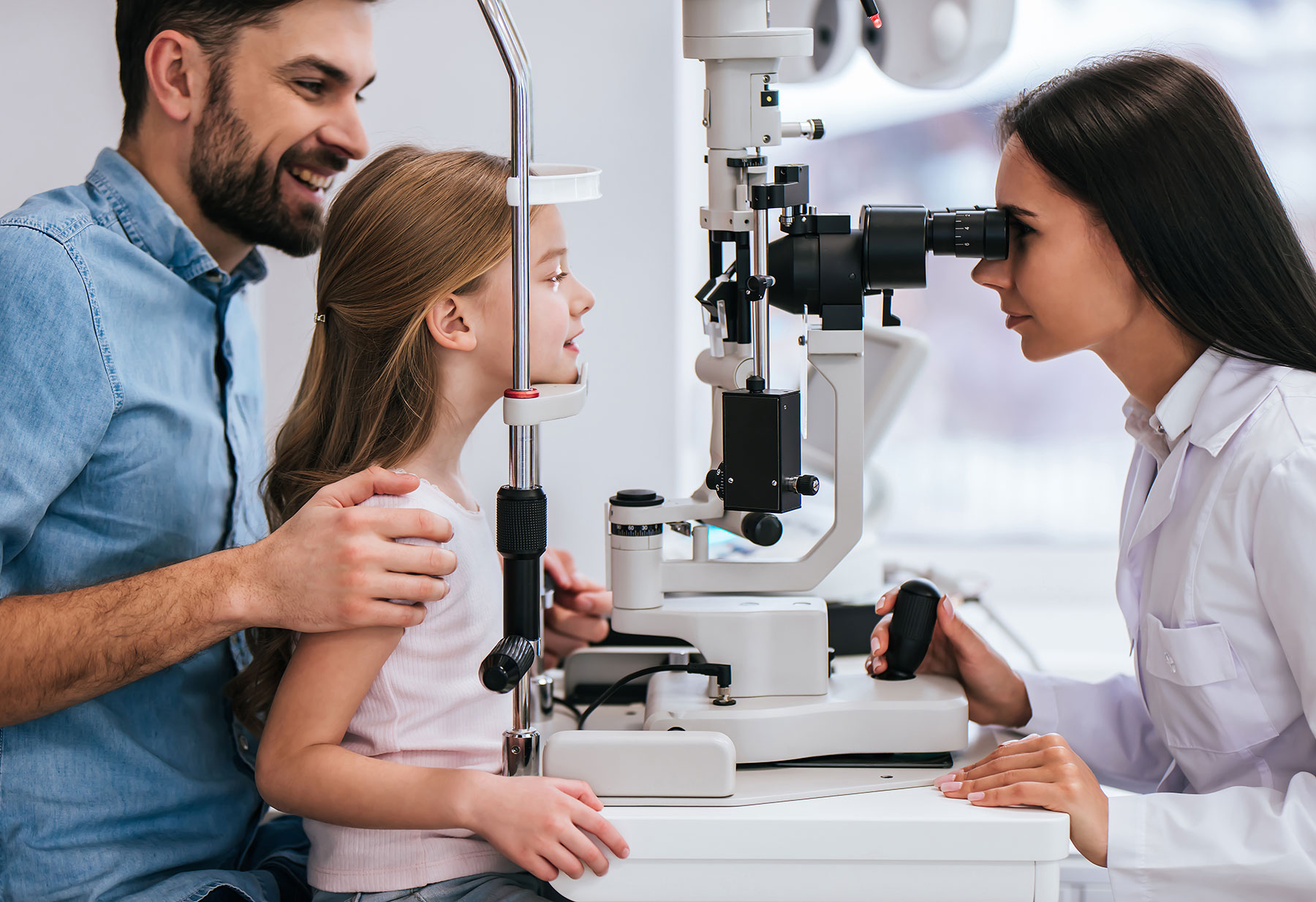 dad helping daughter in eye exam